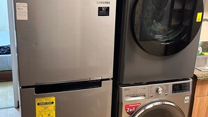 A Samsung refrigerator and LG washer stacked together in a kitchen.