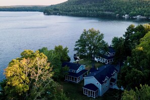 A lakeside property with multiple houses, a dock, and a forested backdrop. - Step-free lake house, screened porch (Dedham)