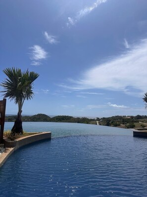 A clear blue sky, a swimming pool, and a distant view of a hilly landscape.