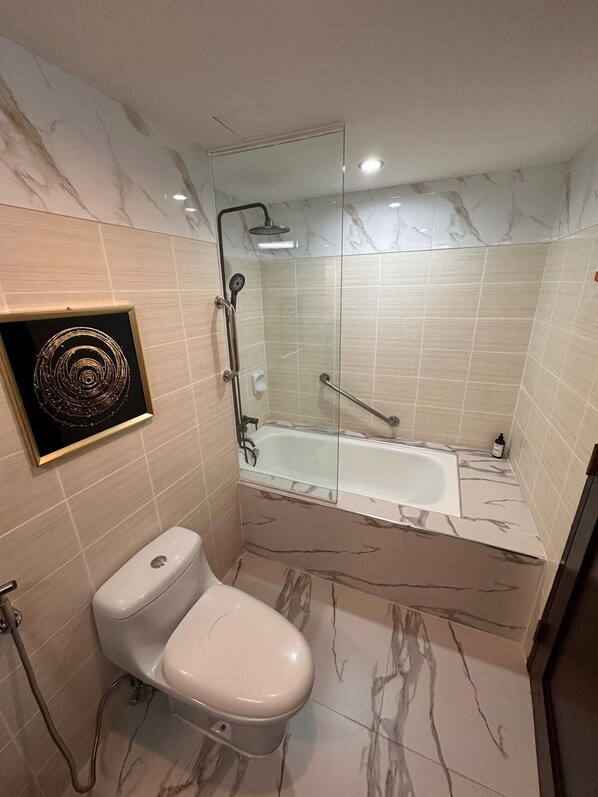 A modern bathroom with a glass-enclosed shower, a white toilet, and marble-patterned tiles.