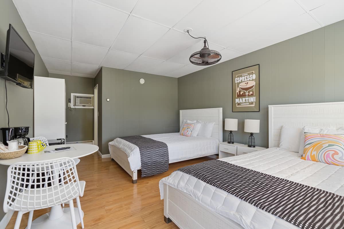 A hotel room with two beds, a dining table, and a TV.