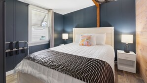 A bedroom with a bed, bedside tables, a window with blinds, and a ceiling fan.