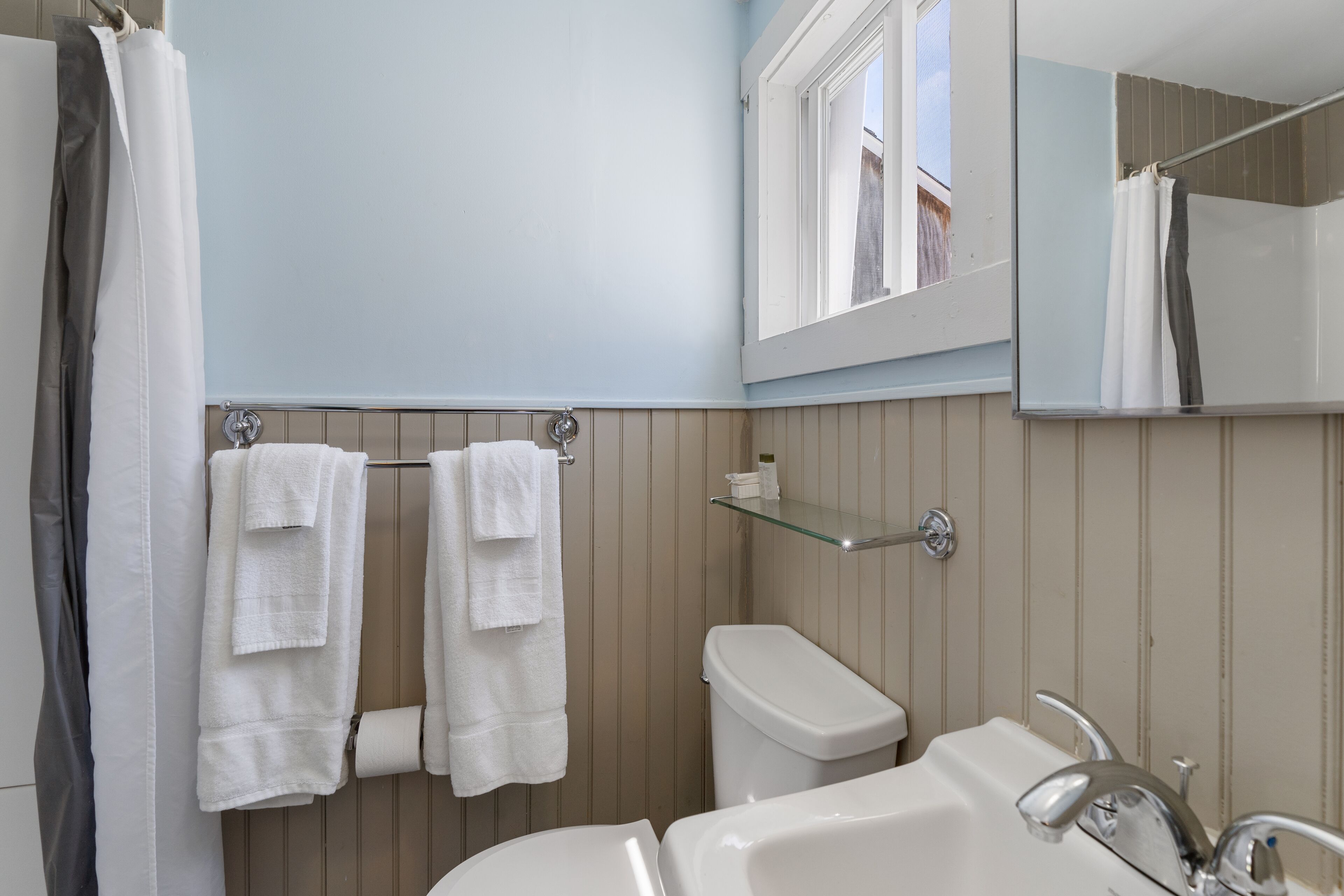 A bathroom with a toilet, sink, and a mirror above the sink.