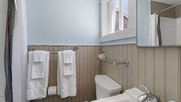 A bathroom with a toilet, sink, and a mirror above the sink.