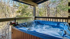 A hot tub with a wooden deck and railing, surrounded by trees. - Award winner| Dollywood |Arcades|Hot tub |GSMNP (Sevierville)