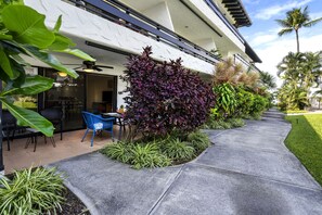 Ein modernes Gebäude mit überdachter Terrasse, Außenmöbeln und üppiger Bepflanzung.