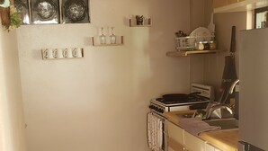 A compact kitchen with a stove, sink, and cabinets. - Adorable 1-bedroom Pet-friendly Studio (Cayey, PR)