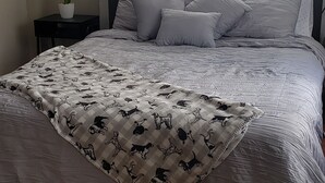 A bedroom with a bed, a nightstand, a lamp, and a window with curtains. - Adorable 1-bedroom Pet-friendly Studio (Cayey, PR)