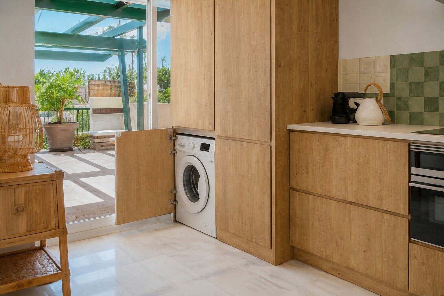 Une cuisine compacte avec des meubles en bois, un lave-linge encastré et une machine à café.
