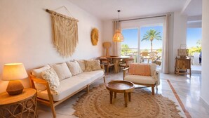A living room with a sofa, armchairs, a coffee table, and a large woven rug.