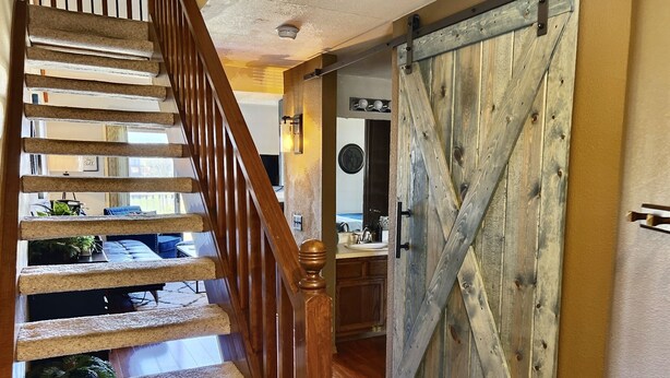 Una escalera de madera que conduce a una sala de estar con una puerta corredera de estilo granero.
