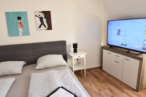 A hotel room with a bed, a TV, a small table, and a cabinet.