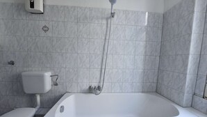 Une salle de bain avec une baignoire, des toilettes et une douche.