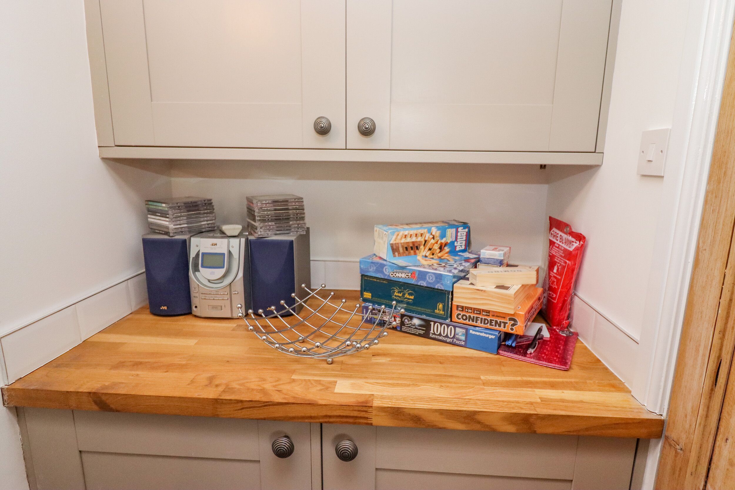 Een aanrecht met een magnetron, waterkoker en verschillende keukenspullen, waaronder een doos met Connect 1000 puzzelstukjes.