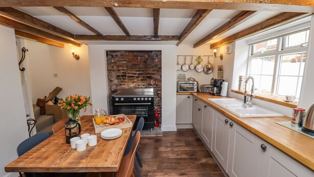 A kitchen with a wooden table, a brick wall, and a window.
