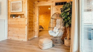 Un intérieur en bois avec une chaise en osier, une plante en pot et un tableau encadré au mur.