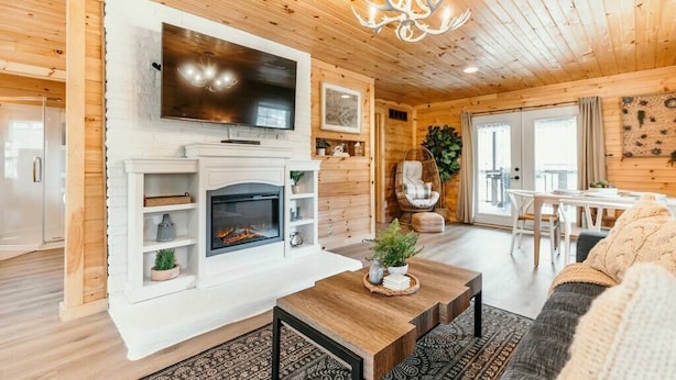 Un intérieur de chalet chaleureux avec une cheminée, un téléviseur, des murs en bois et un coin repas.