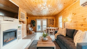 L’intérieur chaleureux d’un chalet comprend une cheminée, un coin repas et un salon avec un canapé.