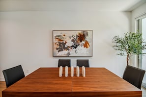 Une table de conférence avec des chaises, un tableau abstrait encadré et une plante en pot.