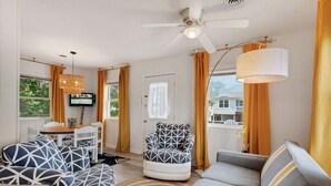 A living room with a ceiling fan, a TV, and a dining area with a table and chairs. - 5041 The Captains Quarters *1 Block to Boat Access (Kill Devil Hills)