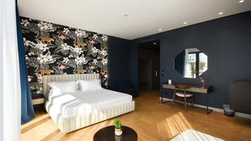 A modern hotel room with a large bed, a desk, a chair, and a mirror.