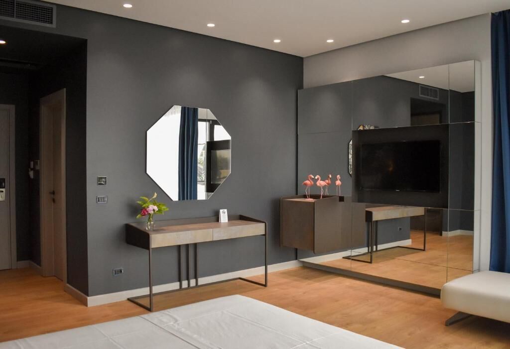 A modern bedroom with a large mirror, a TV, and a minimalist design.