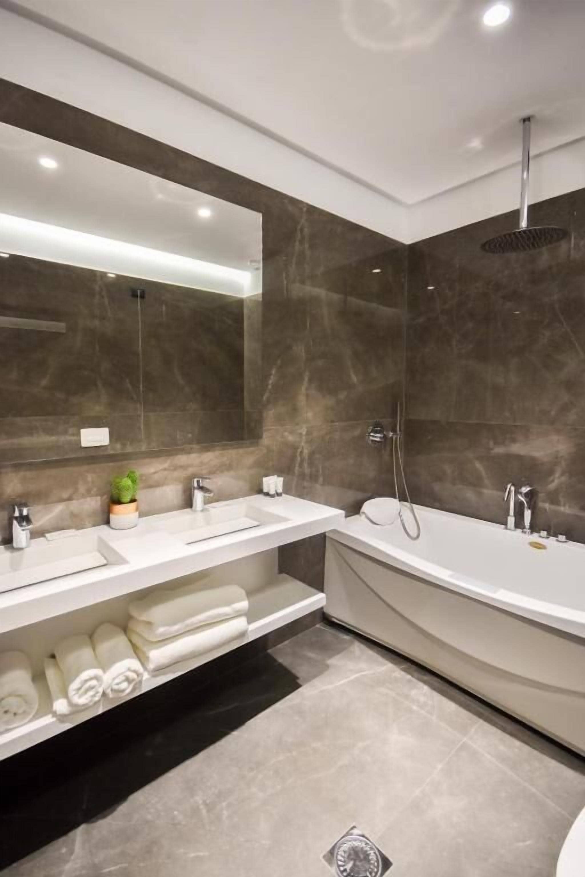 Een moderne badkamer met twee wasbakken, een badkuip en een grote spiegel.