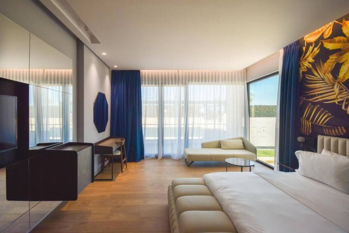 Una camera d'hotel moderna con un grande letto, una poltrona, un tavolino e una televisione.
