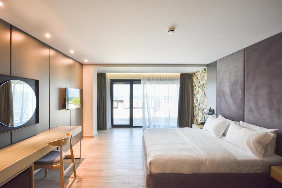 Una camera d'hotel moderna con un letto grande, una scrivania e una TV.