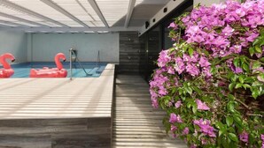 Ein Hallenbad mit Holzterrasse und einem Topf mit Bougainvillea.