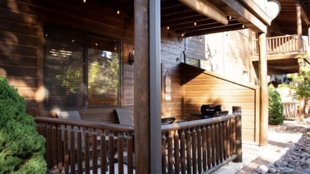 Een houten chalet met een balkon, een pad van stenen en een kleine tuin.