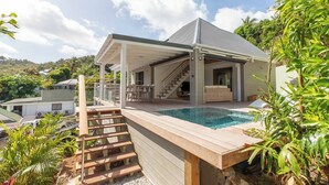 Ein modernes Haus mit Pool, Holzterrasse und überdachter Terrasse.