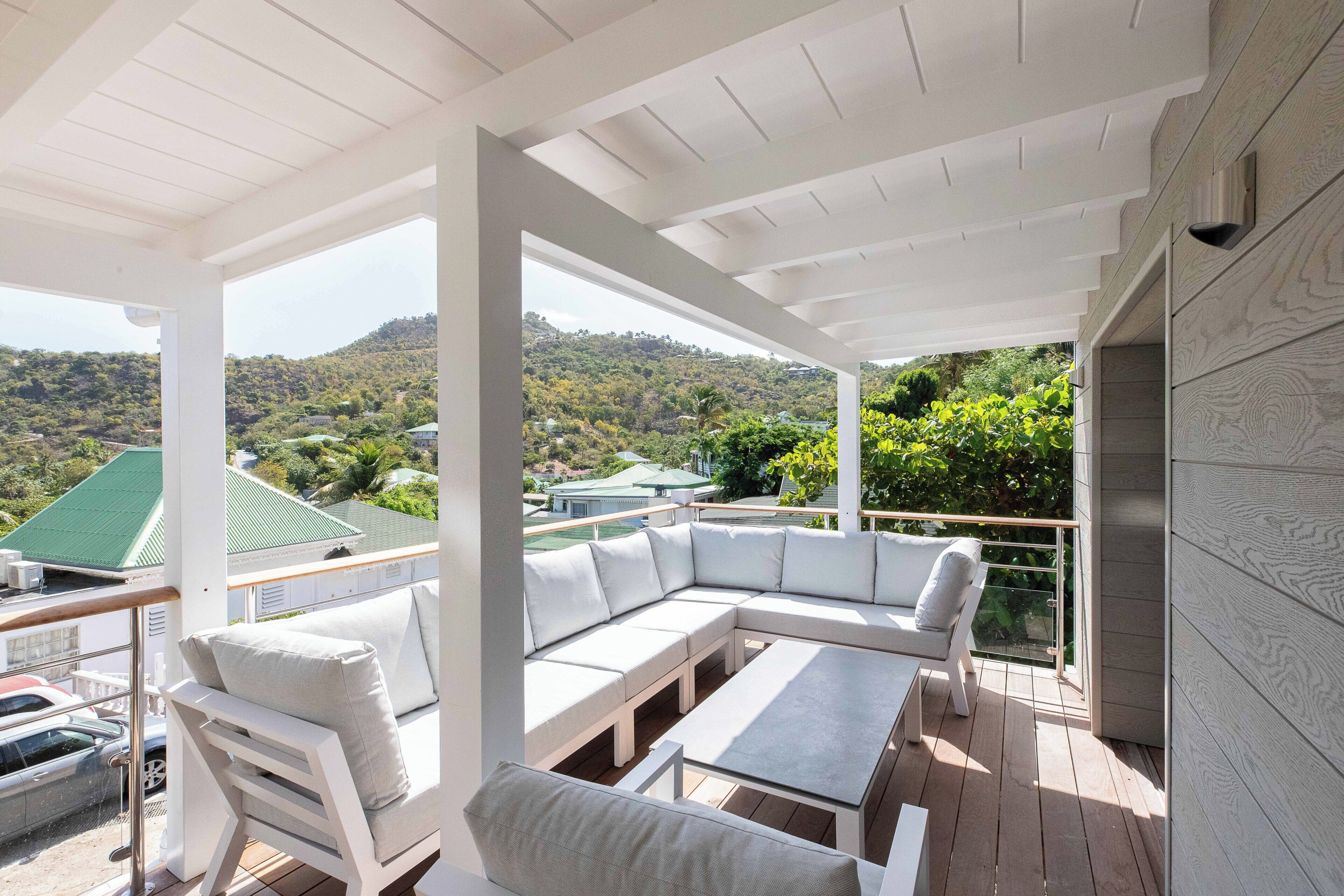 A covered outdoor seating area with a view of a hilly landscape.