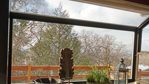 Una ventana con vista a árboles y una terraza de madera.