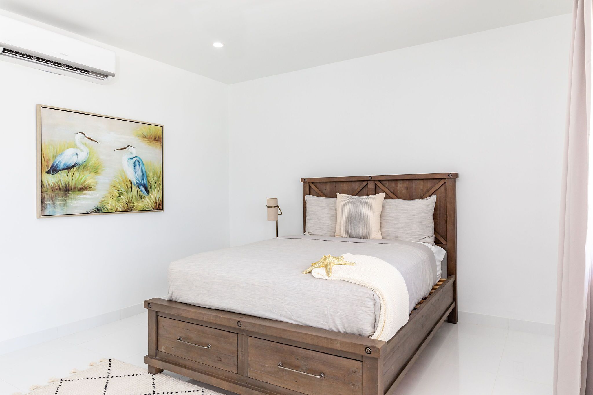 A bedroom with a wooden bed, a nightstand, a lamp, and a painting of birds.