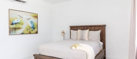 A bedroom with a wooden bed, a nightstand, a lamp, and a painting of birds.