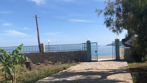 A paved pathway leading to a gated area with a stone wall and metal fence.