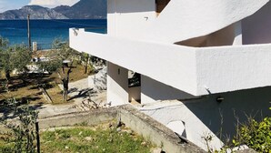 A modern white building with a balcony overlooking a body of water and mountains.
