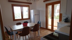 A compact kitchen with a refrigerator, a dining table with chairs, and a washing machine.