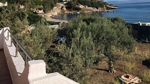 A coastal view with buildings, trees, and a clear sky.