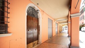 A corridor with a wooden door, a metal staircase, and a closed shutter door. - HouSmart San Carlo 17 (Bologna)
