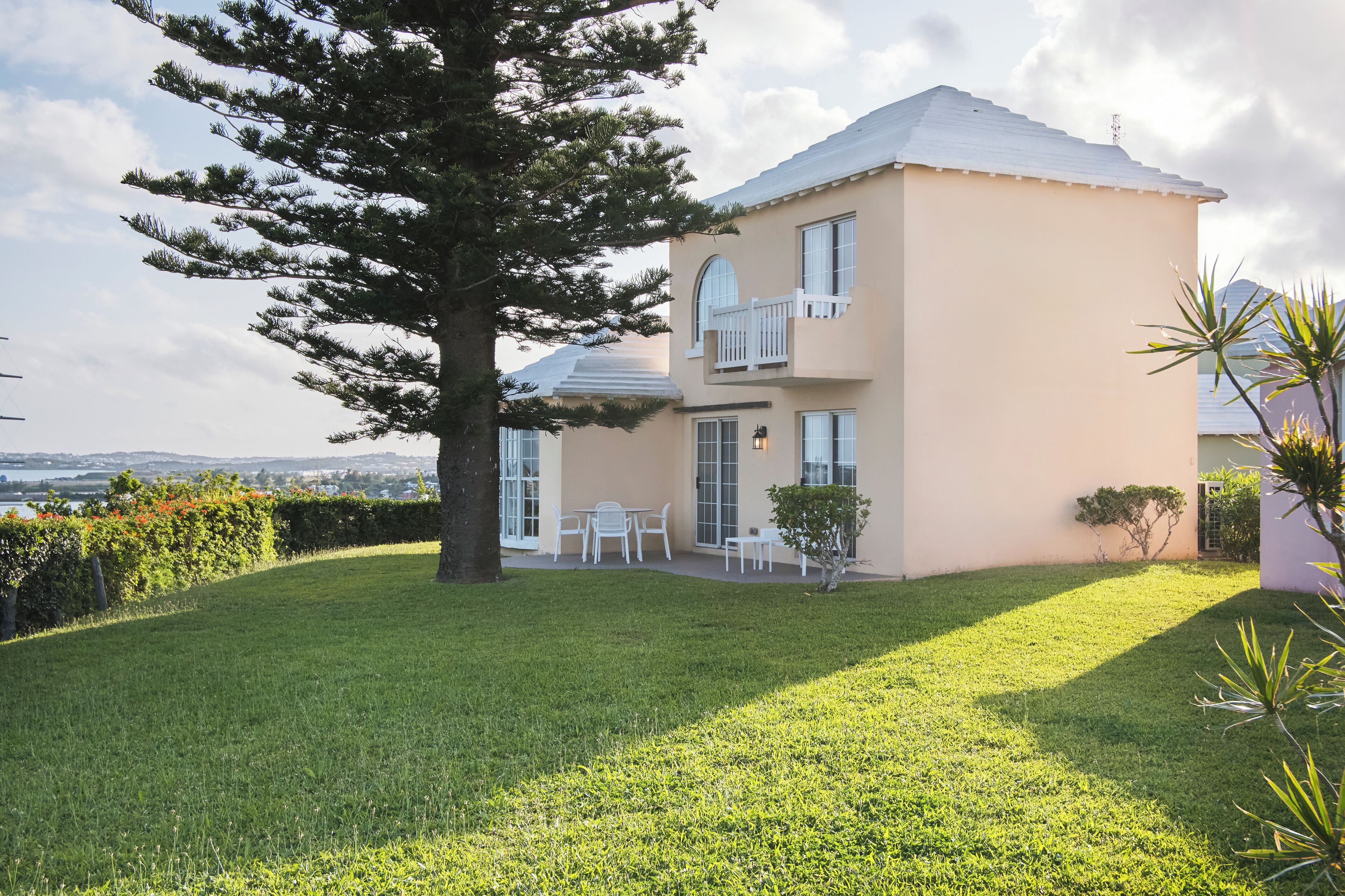 A two-story house with a balcony, a lawn, and a view of the landscape.