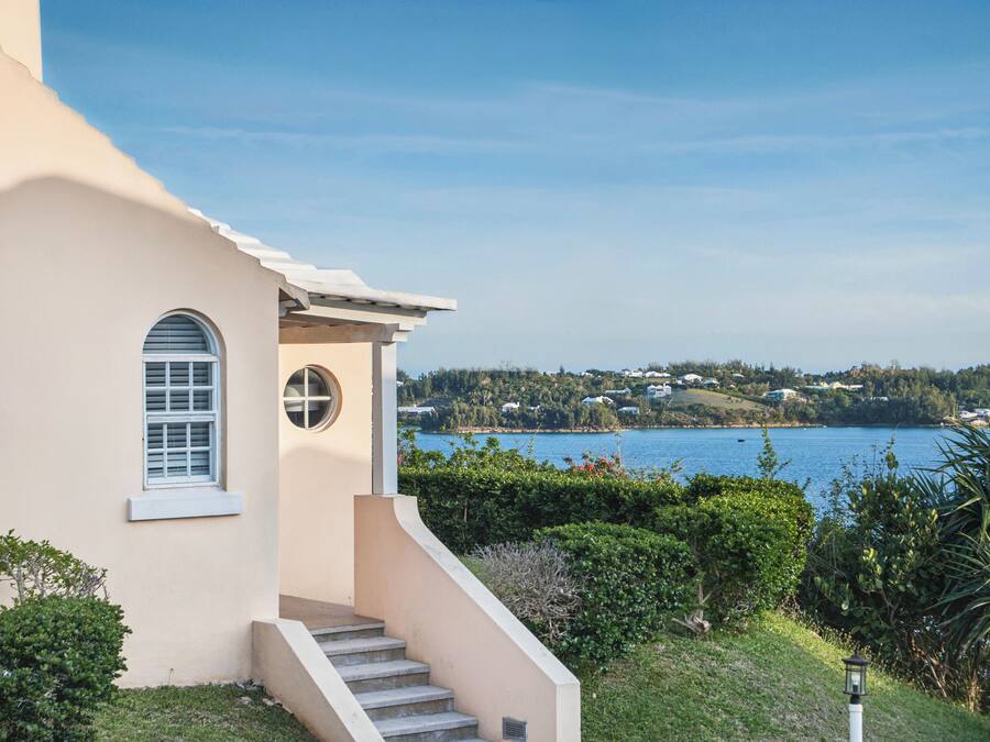 Ein Haus mit einer Treppe zu einem Balkon mit Blick auf einen See und Hügel.