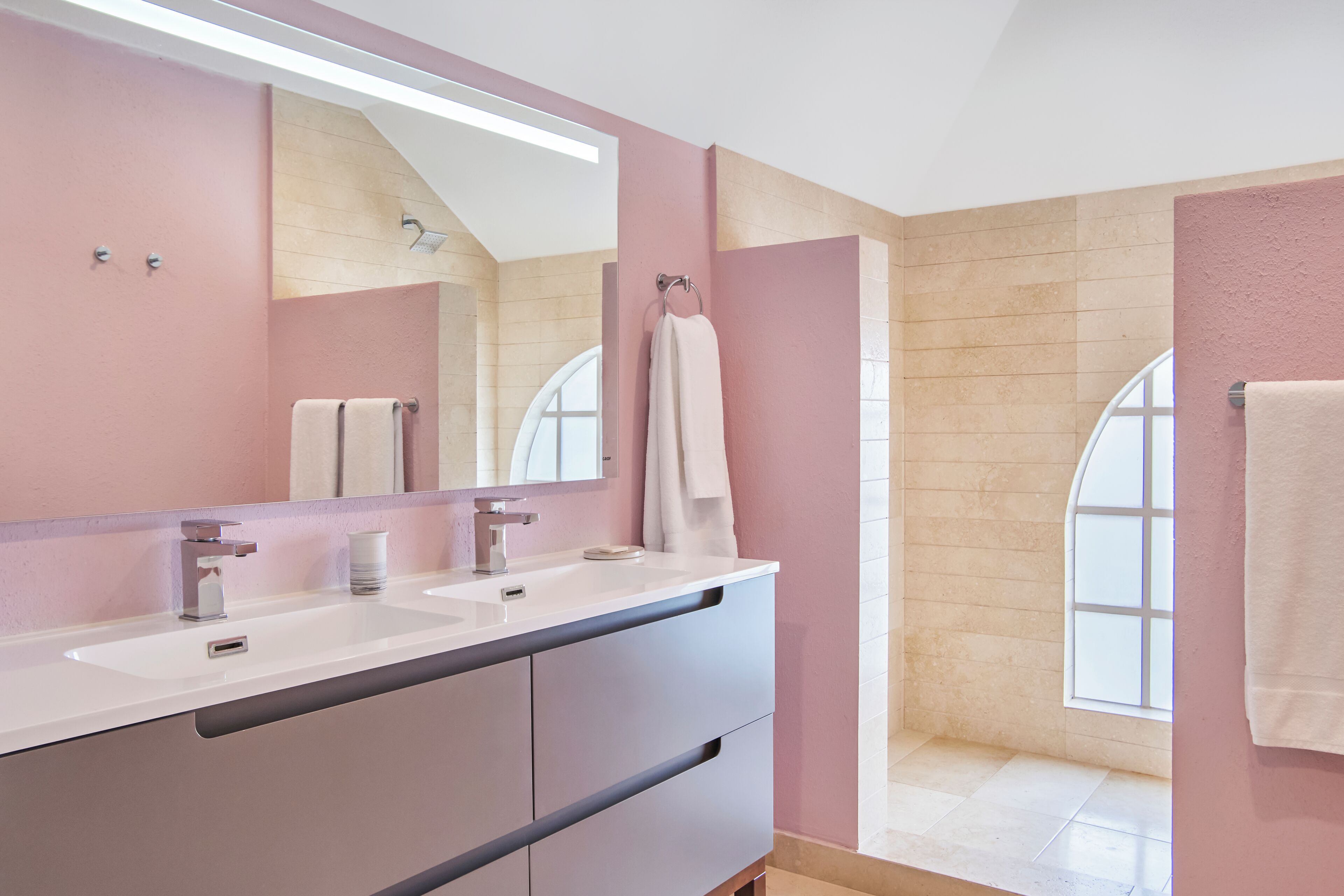 Une salle de bain moderne avec deux lavabos, un grand miroir et une fenêtre.