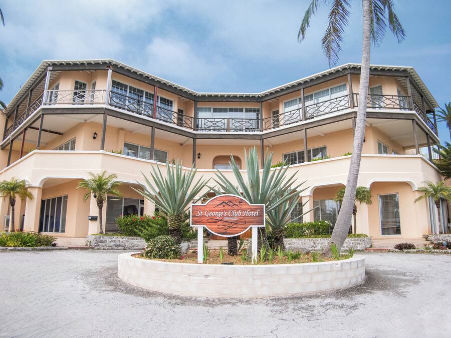 A multi-story hotel with a sign reading "St George's Club Hotel" surrounded by palm trees and a landscaped area.
