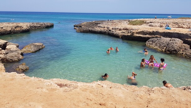 A rocky beach with clear water and people swimming and relaxing. - Javec patio 2 minutes from town center, 10 minutes from the sea and (Carovigno)