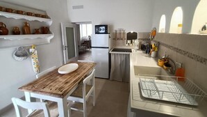 A compact kitchen with white cabinetry, a wooden dining table, and a built-in dishwasher. - Javec patio 2 minutes from town center, 10 minutes from the sea and (Carovigno)