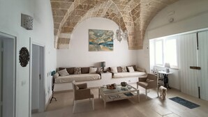 A living room with a stone ceiling, a sofa, a coffee table, and a painting. - Javec patio 2 minutes from town center, 10 minutes from the sea and (Carovigno)