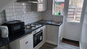 Une cuisine compacte équipée d’une cuisinière à gaz, d’un four à micro-ondes et d’un petit réfrigérateur.