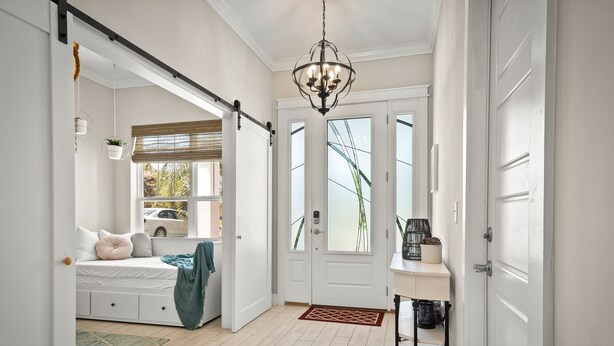 A modern interior with a sliding door leading to a bedroom, a chandelier, and a small table with a plant. - 4 blocks from beach! spacious getaway w game room, outdoor kitchen. Kid-friendly (Jacksonville Beach)